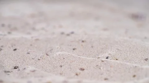 Sand patterns on beach with small stones and shells at low tide during daylight Stock Photos