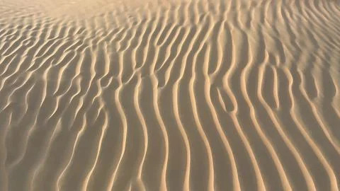 Sand patterns form gracefully in desert, with wind-swept ridges and smooth Stock Photos