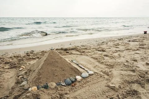 A sand pyramid decorated with smooth pebbles on a scenic beach by the sea Stock Photos