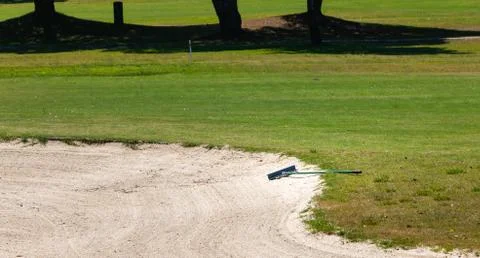 Sand rake lying in a bunker on a golf course Stock Photos