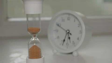 Sand runnning in hourglass with clock at background Stock Footage 128447331