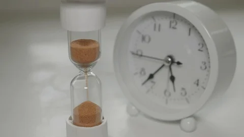 Sand runnning in hourglass with clock at background Stock Footage 128447508