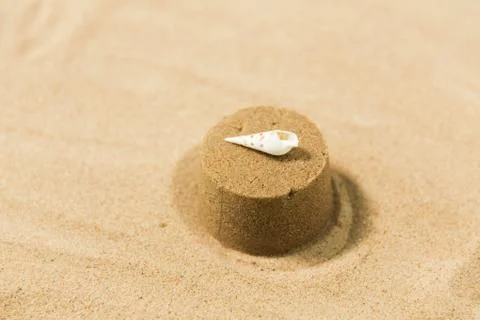 Sand shape made by mold with shell on summer beach Stock Photos