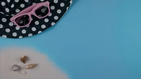 Sand with shells, panama and sunglasses appear on a blue background. Stop motion 動画素材 194413778