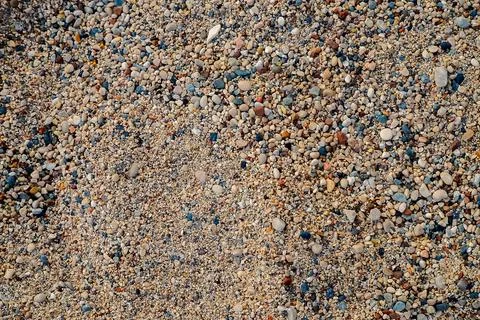 Sand is spread across beach with small stones mixed in. setting shows no peop Stock Photos