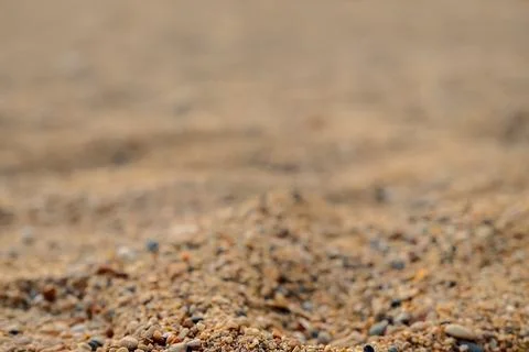 Sand is spread across beach with small stones mixed in. setting shows no peop Stock Photos