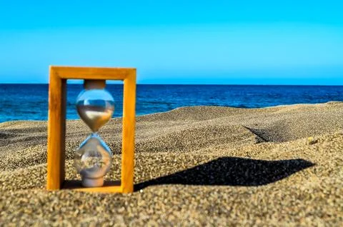 A sand timer is on the beach next to the ocean Stock-Fotos