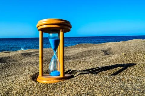 A sand timer is on the beach with the ocean in the background Stock Photos
