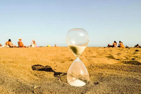 A sand timer is on the beach with people in the background Foto stock