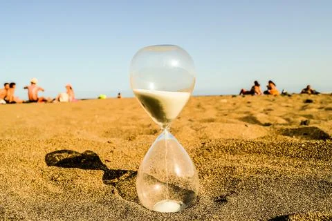 A sand timer is on the beach with people in the background Stock Photos