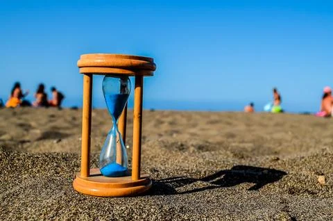 A sand timer is on the beach with people in the background Stock-Fotos