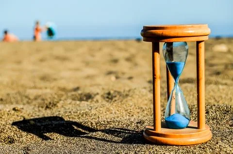 A sand timer is on the beach with a person in the background Foto stock