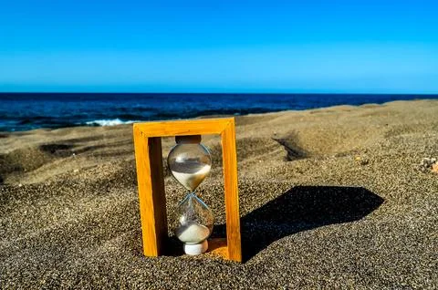 A sand timer is on the beach, with the sand timer showing the time as almost  Stock-Fotos
