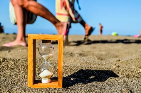 A sand timer is sitting on the beach Stock Photos