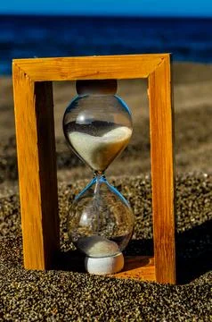 A sand timer is sitting on the beach Stock Photos