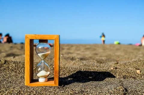 A sand timer is sitting on the beach 스톡 사진