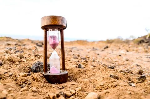 A sand timer is sitting on a rocky surface Stock-Fotos