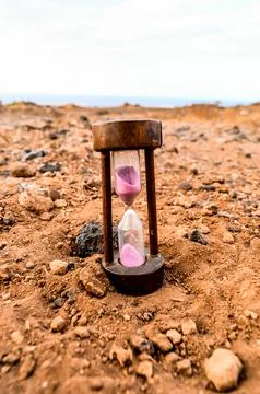 A sand timer is sitting on a rocky surface Stock Photos