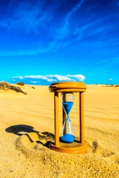 A sand timer is sitting on the sand in the desert Stock Photos
