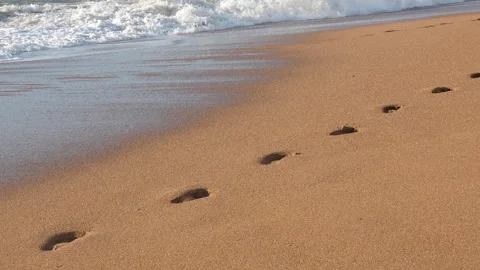 Sand waves erasing human footprints, washing away traces along shoreline Video stock 308706235