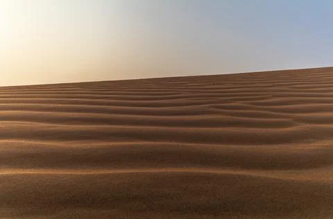 Sand waves on the red dunes in the desert near Dubai at sunrise Stock Photos