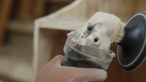 A sander grinds a board in a carpentry workshop, sanding a cabinet or chest of Stock Footage 256547947