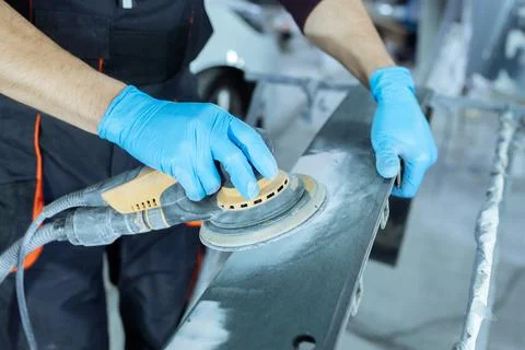 Sanding a car body part with electrical grinder machine before painting, vehicle Stock Photos