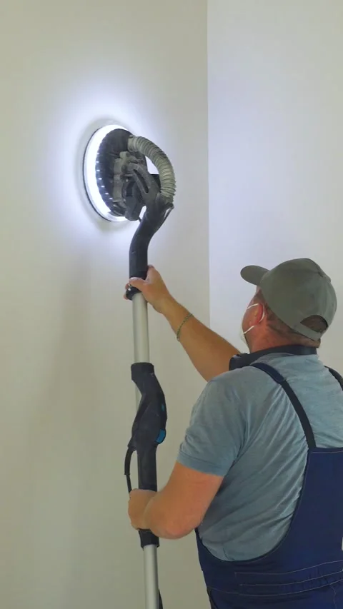 Sanding wall. Construction worker works with modern sanding vacuum cleaner. Man Video stock 324047445