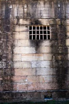 Sandstone brick prison building rusting security grill, wall background Stock Photos