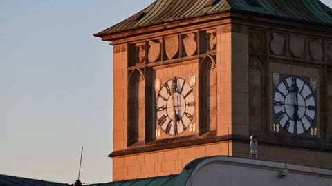 A sandstone clock tower with two Roman numeral clock faces and heraldic shields Stock Footage 342325984