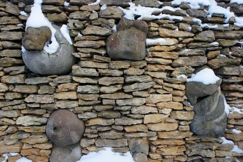 Sandstone wall with inserts of large stone and a little snow Stock Photos