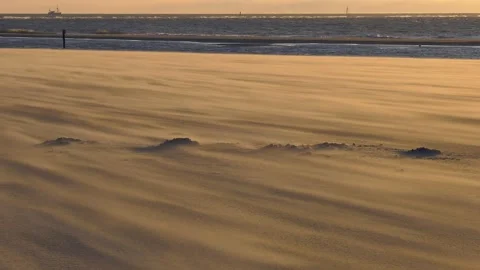 A sandstorm on the beach in the sunset, sand sweeps across the beach by the sea 動画素材 235007702