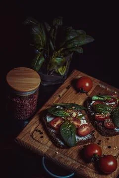 Sandwich with cream cheese, cherry tomatoes, spinach and spices on a wooden Stockfoto's