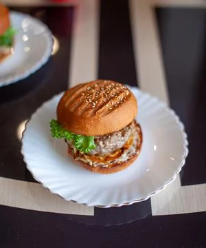 Sandwich with cutlet, cheese and green salad on a plate in the kitchen Stock Photos