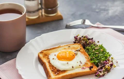 A sandwich with egg in the hole of the bread, microgreens, healthy food Break Foto stock