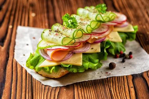 Sandwich with ham, cheese, bacon, radish, lettuce, cucumbers and onions dec.. 스톡 사진