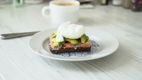 Sandwich with red fish poached egg and avocado behind cup of coffee Stock Footage 232131642