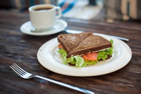 Sandwich of rye bread with red fish and lettuce and a cup of coffee. Foto stock