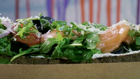 Sandwich with rye bread, salted salmon, cheese, vegetables and herbs. 4K 库存影片 97666529