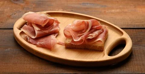 Sandwich with a white square slice of bread and slices of prosciutto Stock Photos