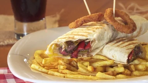 Sandwich wrap with beef meat, cheese and vegetables. Served with french fries Video stock 80261699