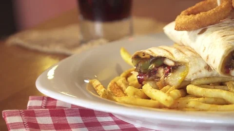 Sandwich wrap with beef meat, cheese and vegetables. Served with french fries Stock Footage 80262078