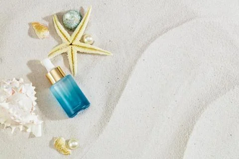 Sandy backdrop showcases a serum bottle adorned with sea shells. Elevate sk.. 写真素材