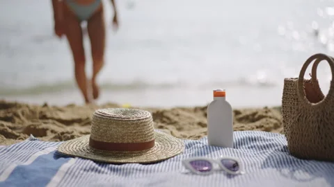 Sandy beach adorned with summer essentials UV protection sun cream, woven straw Stock Footage 270423116
