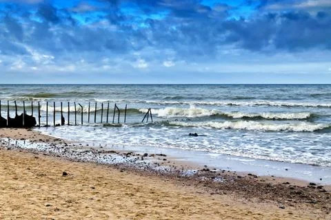 Sandy beach and old rusty breakwater Stock Photos