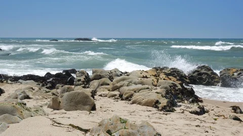 Sandy beach and rocks on Atlantic coast of Portugal as waves throw up spray Видео 95358694
