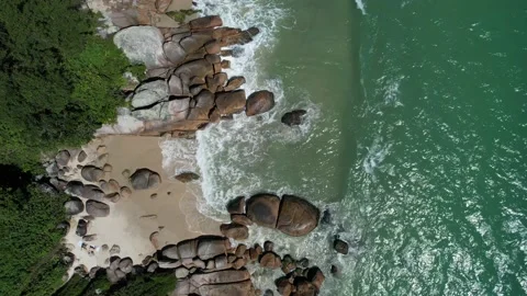 Sandy beach and rocks with foamy wave rolling over in the sun Stock Footage 229853545