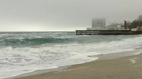 Sandy beach and rough sea,pier and high-rise hotel building in fog,dense clouds Stock Footage 65224576
