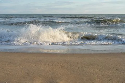 Sandy beach and waves rolling on it Stock Photos