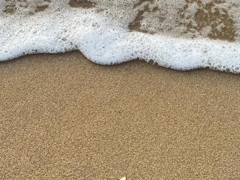 Sandy beach background, shells, white foam waves Stock Photos